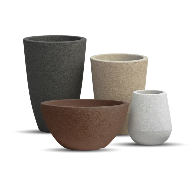 Cuatro macetas de distintos tamaños y colores —negra, beige, marrón y gris— agrupadas sobre un fondo claro.